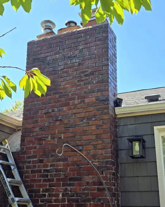 The same brick chimney after cleaning, with clean red brick and several flue pipes on top