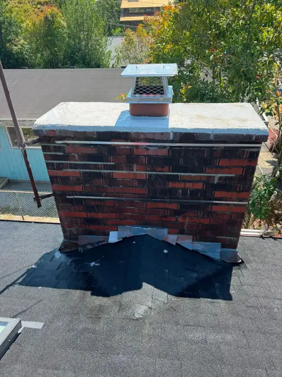 Dark brick chimney with a new white crown, stainless steel straps and metal step flashing at the roof