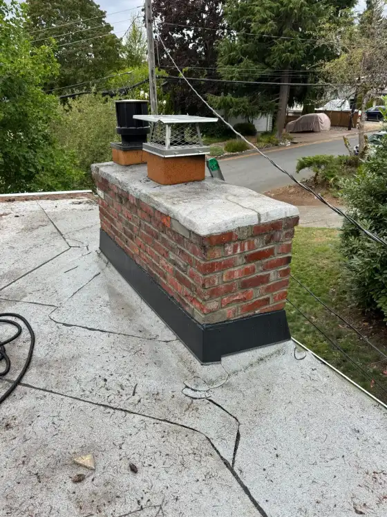 Brick chimney on a flat roof with an old gray crown that is cracked, before repair