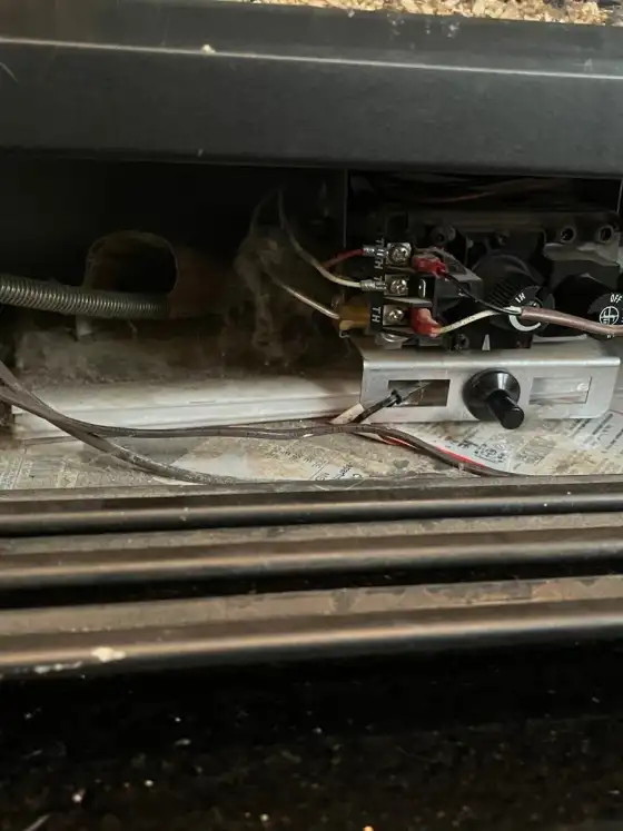 Wider view of the gas fireplace valve and pilot assembly under the burner