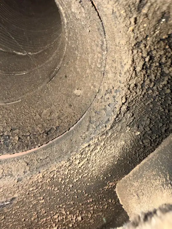 Inside of a chimney flue with a thick layer of soot and creosote on the walls