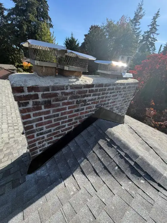 Wide brick chimney with several stainless steel caps in bright sun