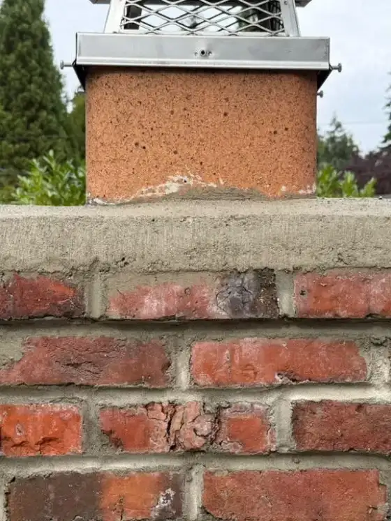 New crown and fresh brick joints below a flue topped with a stainless steel cap